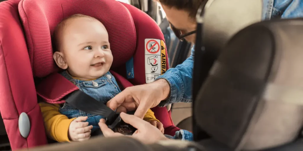parent strapping child in car seat