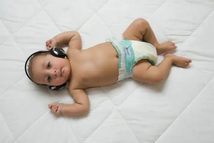 baby in diaper wearing headphones