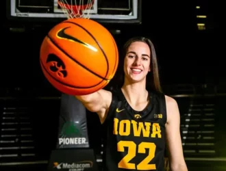 Caitlin Clark of Iowa Stae U holding a basketball with an outsretched arm