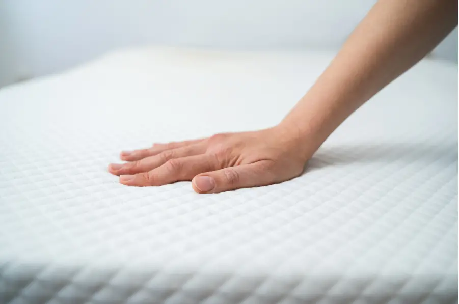 a woman's hand touching a mattress