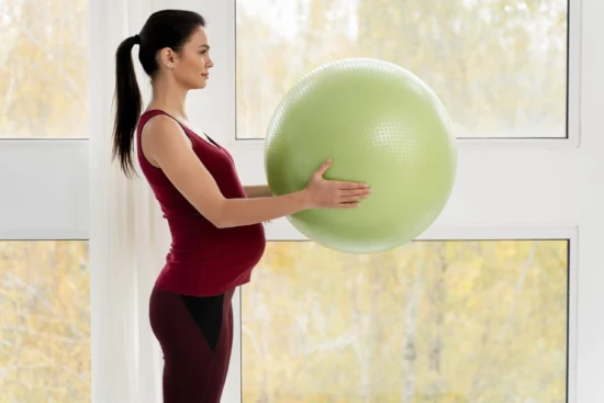 vista lateral mujer embarazada sosteniendo pelota verde fitness min scaled 2