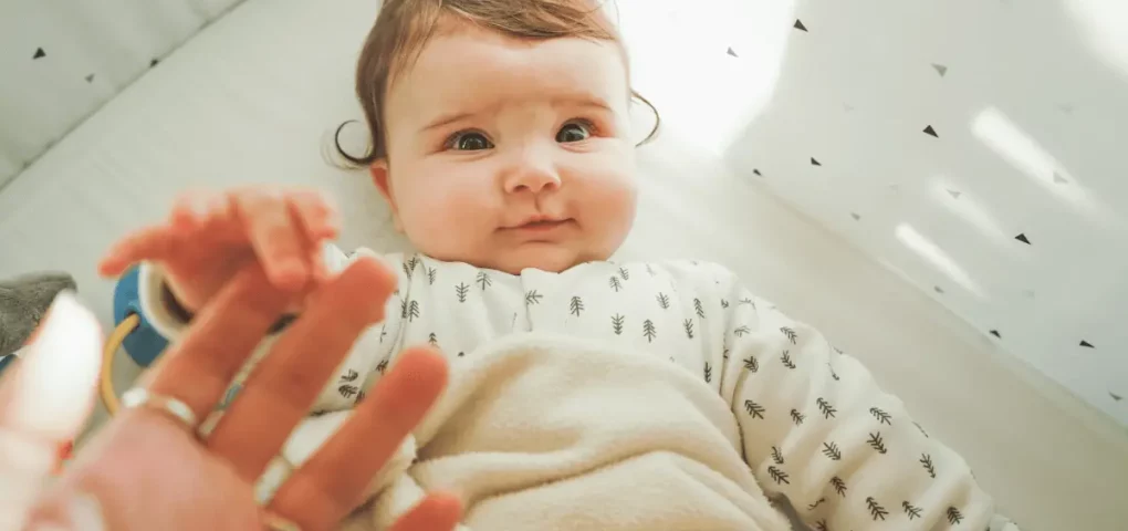 an infant holding mom's finger