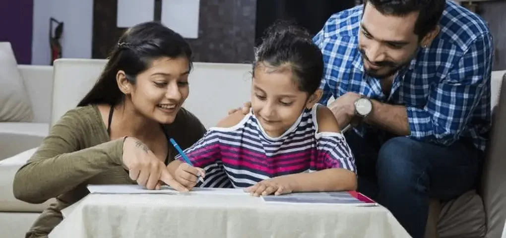mom helping her daughter with assignment while dad looks on