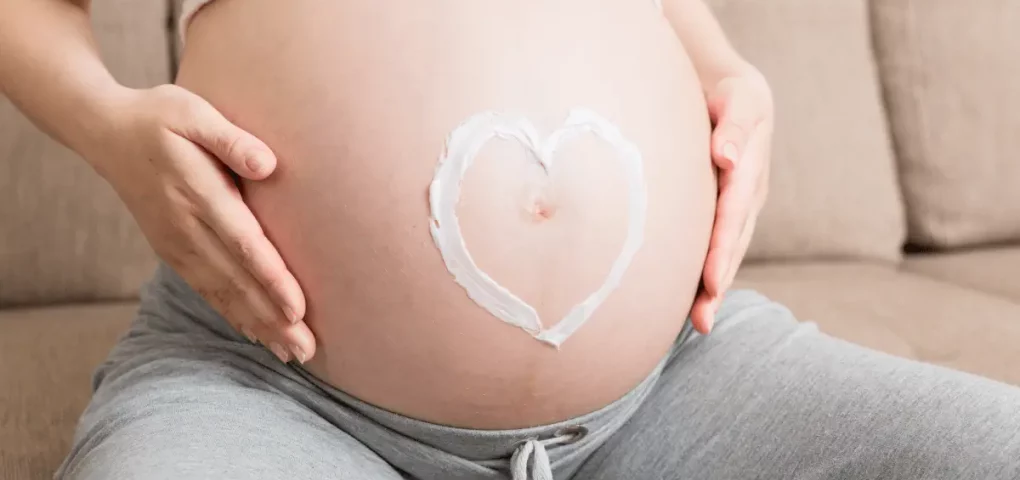 pregnant mom using stretch mark cream