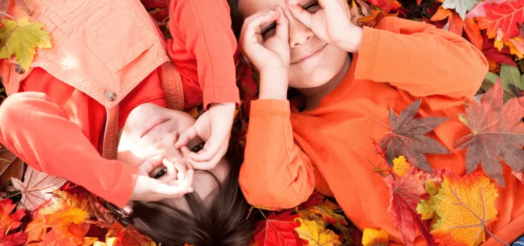 toddlers laying on dried leaves